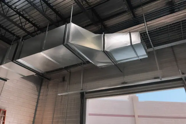 Galvanized steel HVAC ductwork installed on the ceiling of an industrial warehouse in Tempe, AZ.