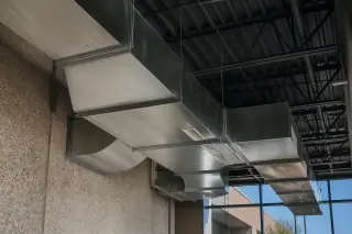 Galvanized steel ductwork installed on a high industrial ceiling with concrete walls in Phoenix, AZ.