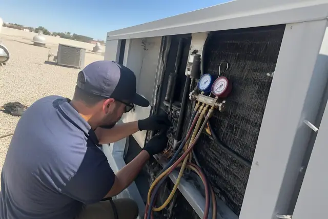 HVAC technician performing a seasonal tune-up on a commercial rooftop unit in Mesa, AZ.