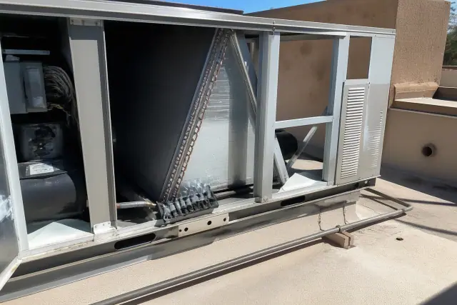 Open commercial HVAC rooftop unit with tools resting on the frame during a maintenance tune-up in Gilbert, AZ.