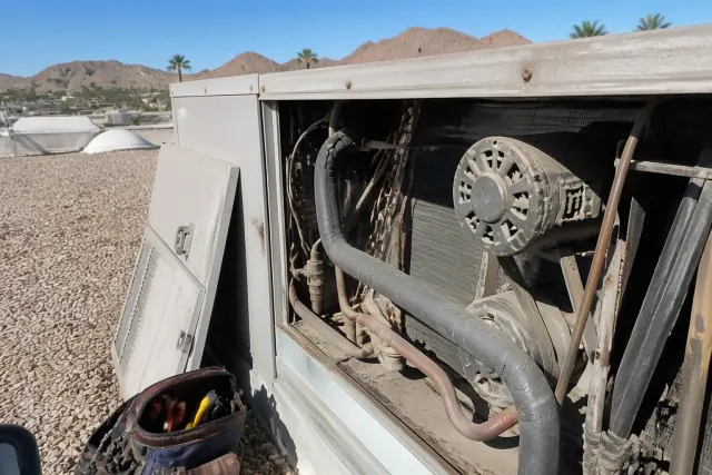 HVAC technician performing a seasonal maintenance tune-up on a rooftop unit in Phoenix, AZ.