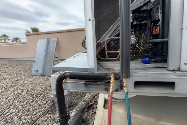 Technician performing a seasonal HVAC tune-up on a rooftop unit at a commercial building in Chandler, AZ.