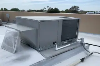 Maintained HVAC unit on a white roof with a used filter in a disposal bag in Phoenix, AZ.