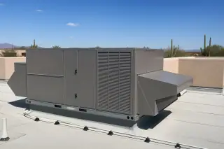 Large commercial HVAC unit on a flat rooftop with stucco walls and saguaro silhouettes in Phoenix, AZ.