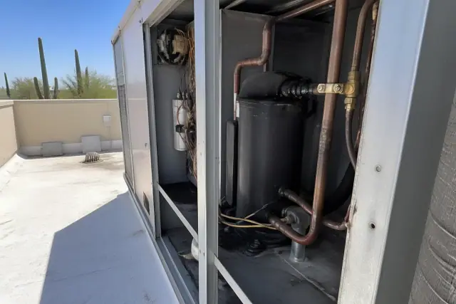Technician performing a seasonal tune-up on a commercial HVAC rooftop unit in Chandler, AZ.