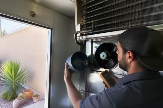 A technician repairing a walk-in cooler evaporator fan motor in Phoenix, AZ.