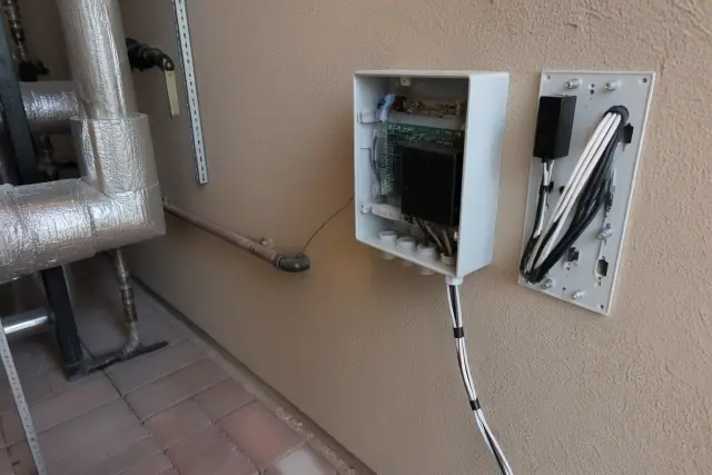 Wall-mounted indoor air quality sensor with exposed wiring in a mechanical room in Phoenix, AZ.
