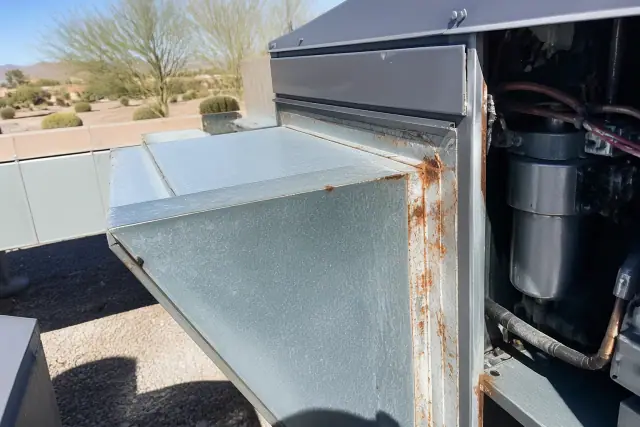 Reddish-orange corrosion on a galvanized steel duct connection at a rooftop unit in Phoenix, AZ.