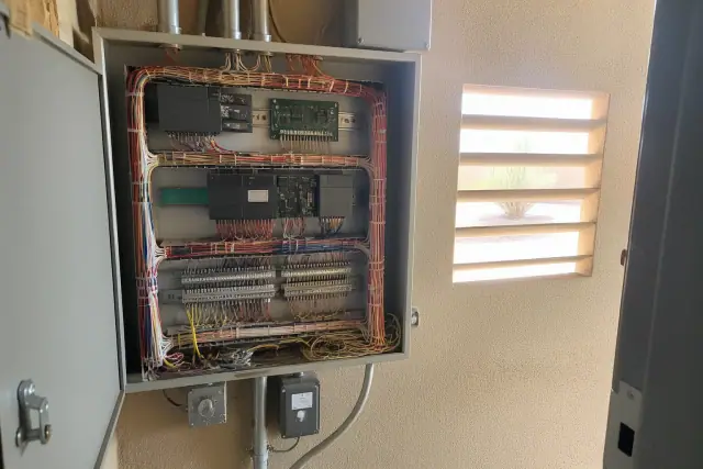 Wall-mounted control cabinet with multi-colored wiring for an HVAC system in a mechanical room in Phoenix, AZ.