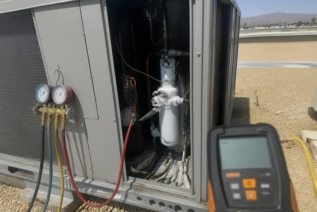 Rooftop commercial HVAC unit with a frosted expansion valve and refrigerant gauges during a repair in Phoenix, AZ.
