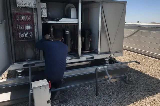 Technician performing seasonal maintenance on a commercial rooftop HVAC unit in Phoenix, AZ.