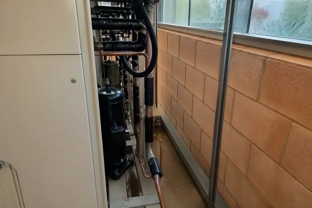 Copper refrigerant lines and a compressor unit in a mechanical room in Phoenix, AZ.