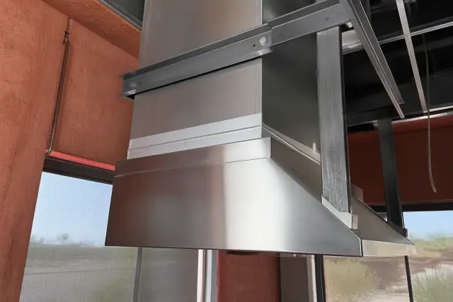 Stainless steel HVAC hood flange installation with mounting bracket and sealant in a Phoenix, AZ restaurant kitchen.