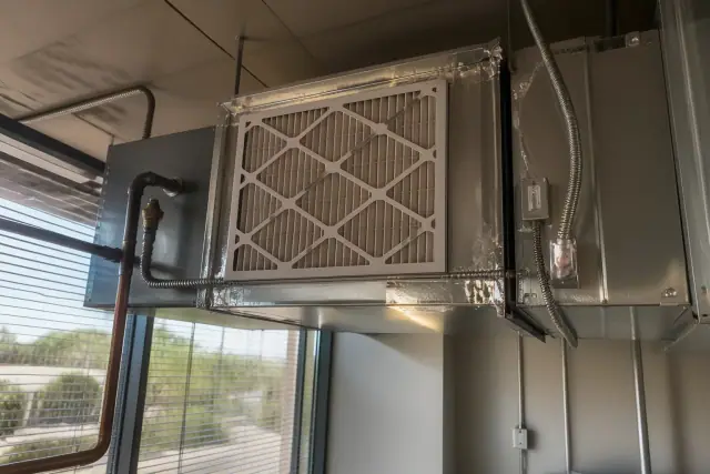 Technician installing a high-efficiency media filter in ductwork at an office facility in Phoenix, AZ.