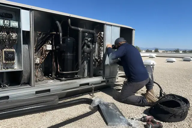 Technician performing a seasonal tune-up on a commercial rooftop unit in Phoenix, AZ.