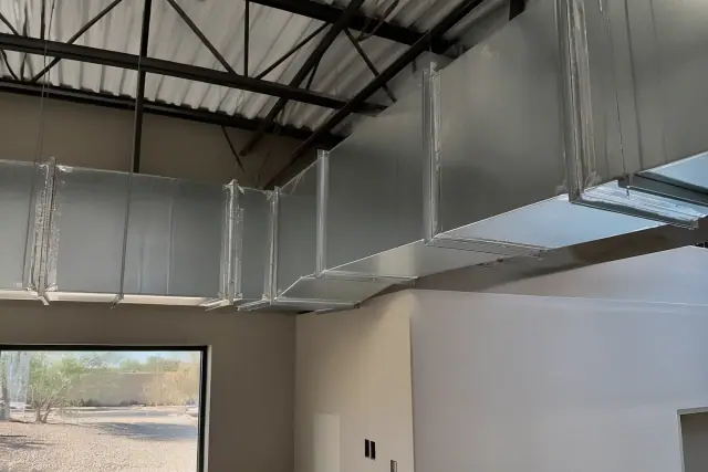 Galvanized steel ductwork suspended from a high industrial ceiling in a warehouse facility in Phoenix, AZ.