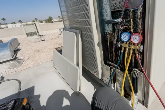 Technician performing VRF maintenance with manifold gauges on a rooftop in Phoenix, AZ.