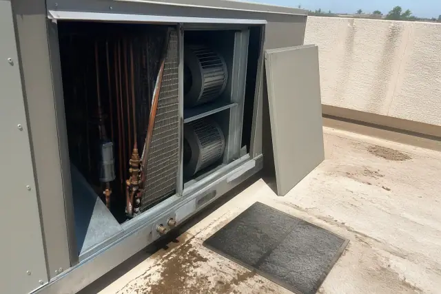 Industrial HVAC unit with open access panel and copper coils on a sunny rooftop in Phoenix, AZ.