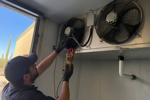 Technician testing an evaporator fan motor in a commercial walk-in cooler in Phoenix, AZ.