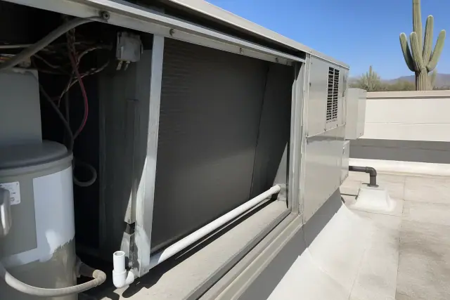 Technician performing seasonal maintenance on a commercial rooftop HVAC unit in Phoenix, AZ.