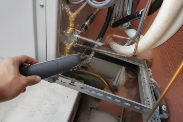 Electronic leak detector wand held over brazed copper refrigerant lines on a VRF system in Phoenix, AZ.