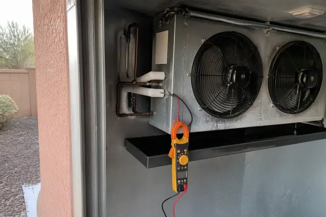 Mechanic testing an evaporator coil fan motor inside a walk-in refrigerator in Phoenix, AZ.