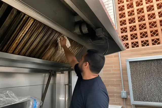 Contractor cleaning grease from a commercial kitchen exhaust hood filter in Phoenix, AZ.