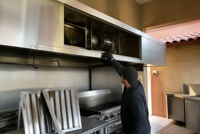 Technician inspecting commercial kitchen exhaust hood components in a Scottsdale, AZ restaurant.