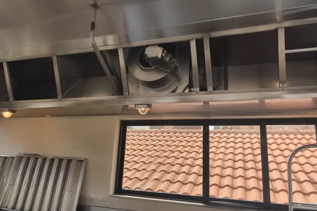 Contractor inspecting a commercial kitchen exhaust hood and blower assembly at a job site in Mesa, AZ.