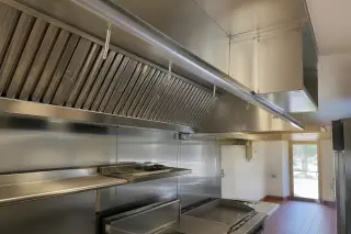 Stainless steel commercial kitchen exhaust hood with grease filters and quarry tile floor in a Phoenix, AZ restaurant.