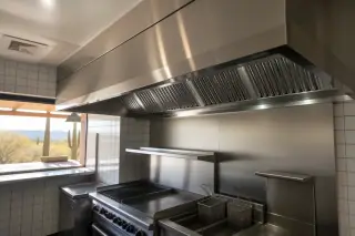 Stainless steel commercial kitchen exhaust hood with grease filters above cooking equipment in Phoenix, AZ.