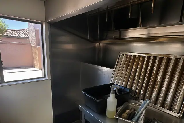 Grease-stained baffle filter being cleaned in a commercial kitchen in Phoenix, AZ.