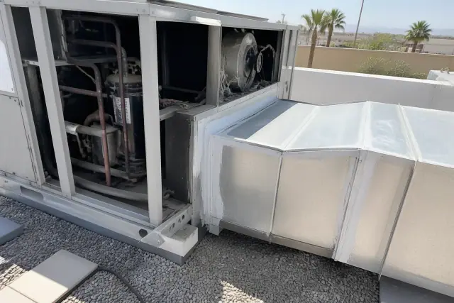 A rooftop HVAC unit with an open panel and fresh silver sealant on a commercial roof in Phoenix, AZ.