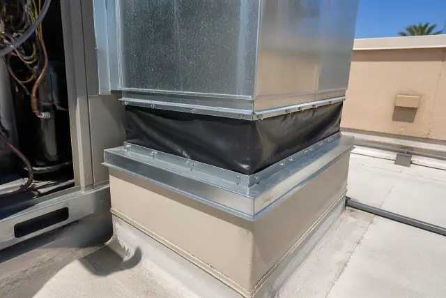 Worker performing a rooftop HVAC duct and curb connection tune-up on a building in Phoenix, AZ.