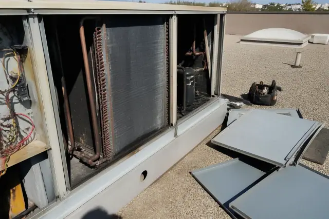 Technician performing a seasonal HVAC maintenance tune-up on a commercial rooftop unit in Phoenix, AZ.