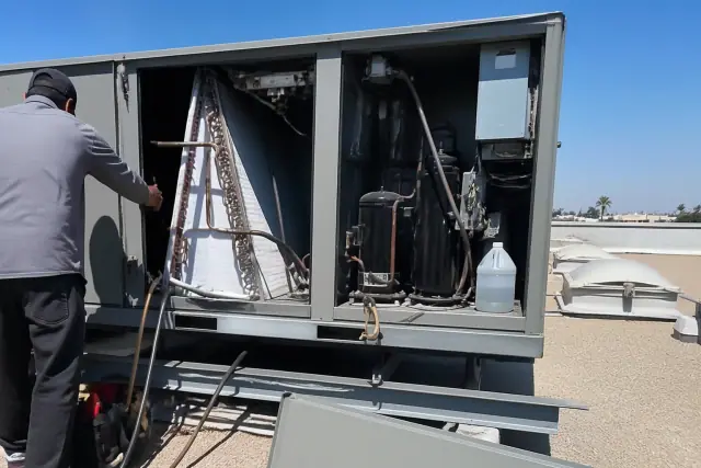 Technician performing a seasonal tune-up on a commercial HVAC rooftop unit in Tempe, AZ.
