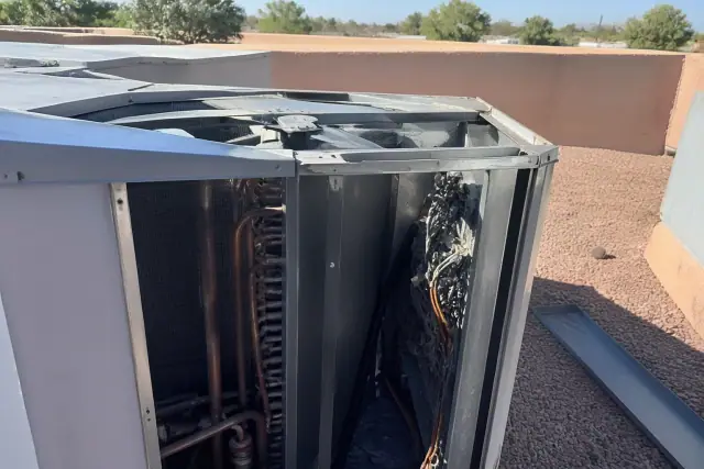 Open commercial HVAC unit with exposed coils and fan blades on a rooftop in Chandler, AZ.