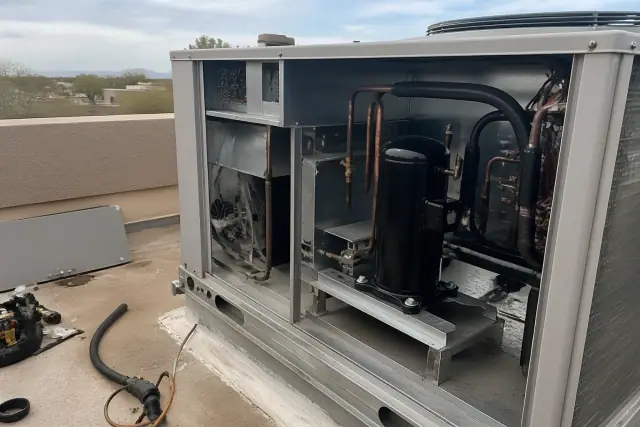 Technician performing a seasonal HVAC tune-up on a rooftop unit at a job site in Goodyear, AZ.