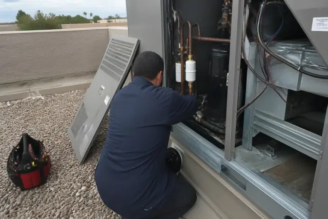 Technician performing a seasonal tune-up on a commercial HVAC rooftop unit in Mesa, AZ.
