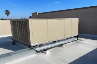 Closed commercial rooftop unit next to a stucco parapet wall under a bright sky in Phoenix, AZ.