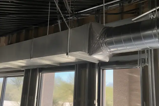 Sheet metal workers installing galvanized steel rectangular and spiral ductwork at a jobsite in Phoenix, AZ.