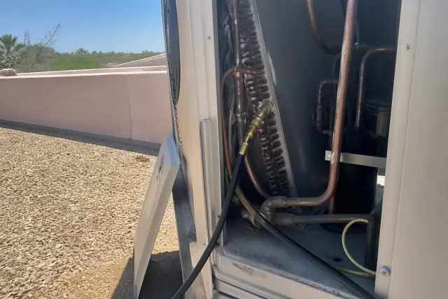 Static-pressure and airflow testing on a rooftop cooling unit in Phoenix, AZ, showing diagnostic hoses on coil manifolds.