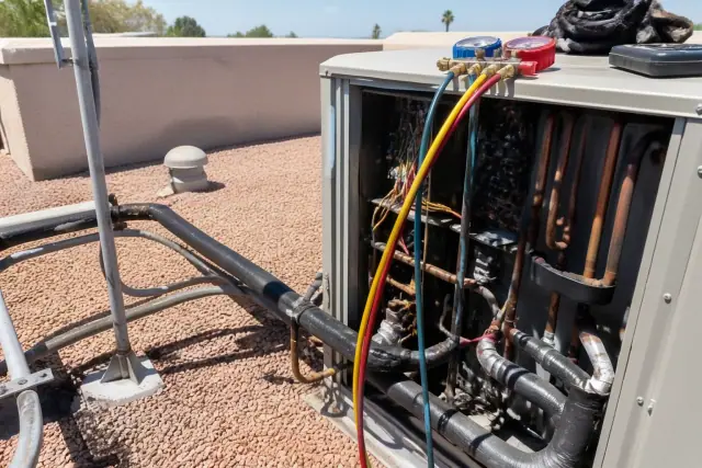 Technician performing VRF system repair on a commercial rooftop in Phoenix, AZ with copper lines and gauges visible.