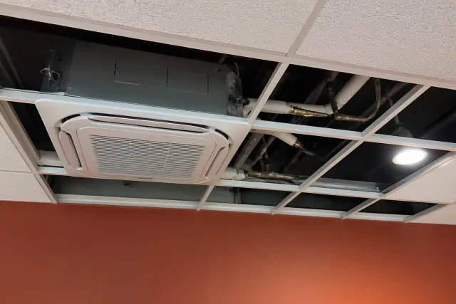 Technician installing a VRF indoor unit in a drop ceiling in Phoenix, AZ.