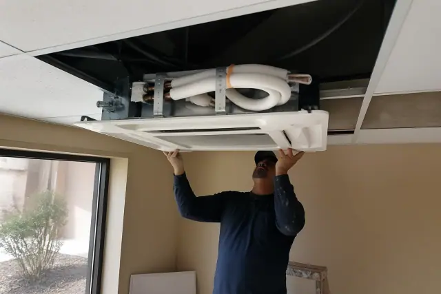 Technician installing a ceiling-cassette VRF unit in an Avondale, AZ commercial building.