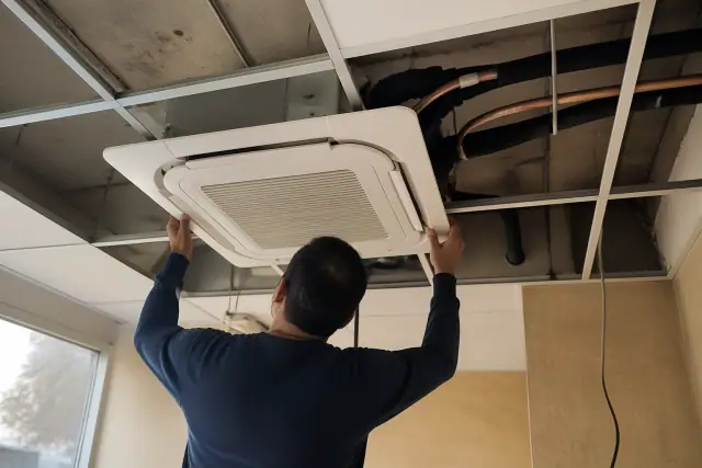 Technician installing a VRF ceiling cassette unit with insulated piping at a commercial jobsite in Chandler, AZ.