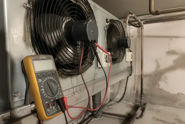 Technician testing an evaporator coil fan motor inside a commercial walk-in cooler in Phoenix, AZ.