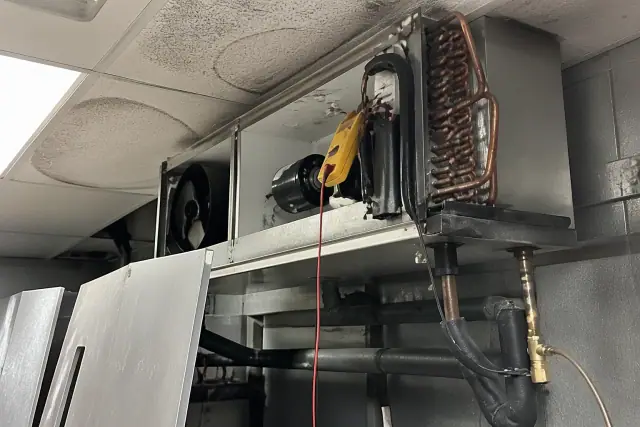 Contractor view of a disassembled commercial refrigeration unit during repair in a Phoenix, AZ restaurant.