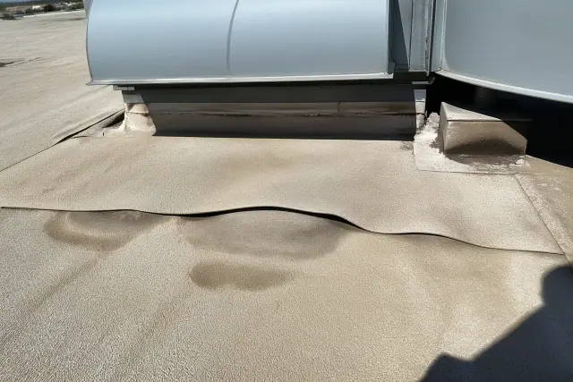 Blistered roof cap sheet with trapped moisture near an HVAC unit on a building in Phoenix, AZ.