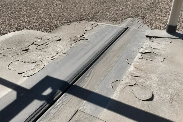 Cracked roof coating and peeling flakes on an expansion joint in Phoenix, AZ.